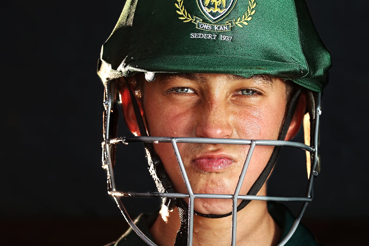 Focused young cricketer wearing a green helmet, preparing for the game.